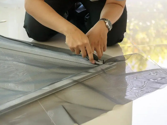 Man repairing a torn window screen in East Brookfield, MA.