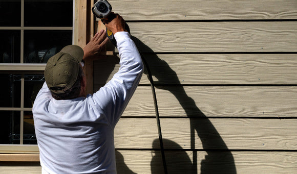 A man trims siding with a power tool, protecting home’s exterior in East Brookfield, MA