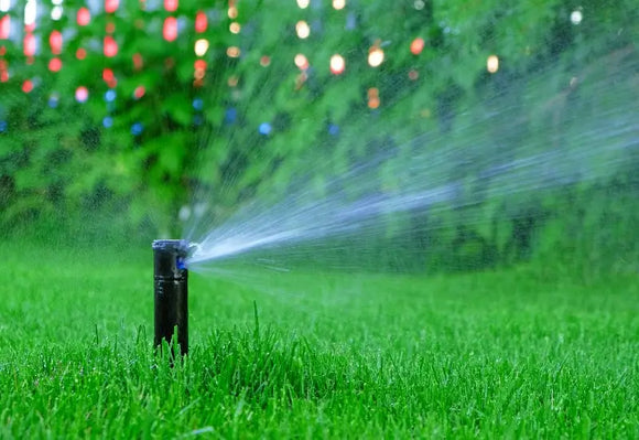 Sprinkler system maintenance with water spraying on a lush green lawn in East Brookfield, MA